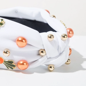 Detail van de witte geknoopte tulband hoofdband met oranje kralen en groene bladeren