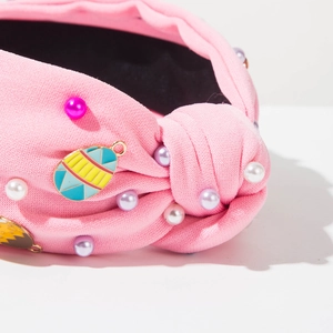 Close-up of pink knotted Easter headband with pearls and colorful egg charm