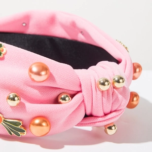 Macro-opname van roze geknoopte haarband met parels en gouden bloemaccenten