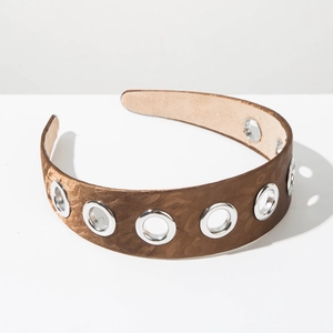 Close-up of vintage brown wide headband with silver metal eyelets and suede lining texture