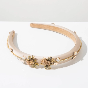 Close-up of champagne satin headband featuring golden bee accents and sparkling crystals