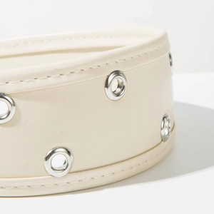 Détail macro du serre-tête en cuir crème avec œillets métalliques argentés et surpiqûres