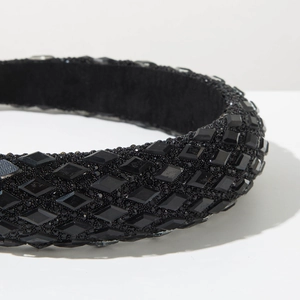 Detailed close-up of a wide black headband featuring sparkling rhinestones and crystal beads