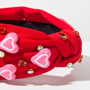 Detailopname van rode geknoopte haarband met roze hartjes en fonkelende strass steentjes