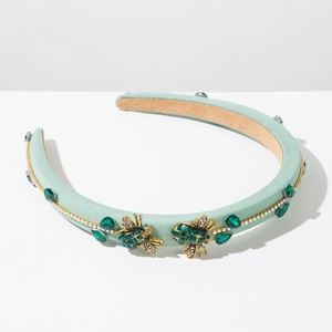 Detail of luxury baroque headband with golden bee accents and emerald green crystals