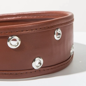 Gros plan d'un serre-tête en cuir marron avec œillets métalliques et coutures fines