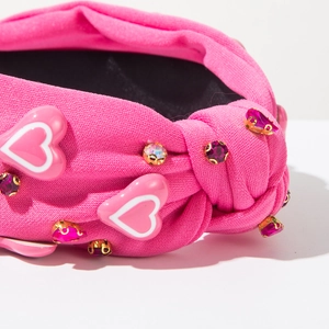 Detail van roze geknoopte hoofdband met fonkelende steentjes en hartvormige patches