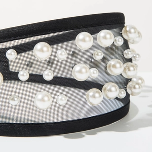 Macro shot of black tulle headband featuring scattered white pearls and fine fabric texture
