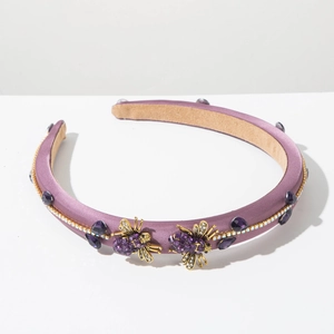 Detail of purple satin padded headband with gold bee accents and purple rhinestones