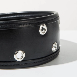 Gros plan sur un serre-tête en cuir noir avec œillets métalliques et coutures fines