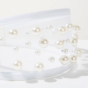 Close-up of white tulle headband featuring glossy faux pearls in a baroque style
