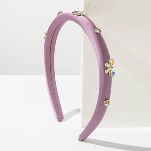 Détail du serre-tête rembourré lavande avec strass colorés et design floral nœud