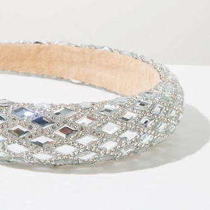 Close-up of sparkling silver rhinestones on a wide headband with soft beige fabric lining