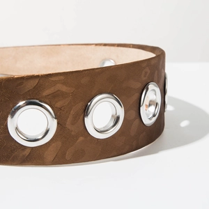 Macro detail of dark brown satin headband with leopard print and silver metal grommets