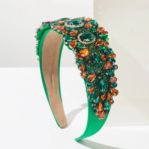 Détail d'un serre-tête baroque vert orné de gemmes émeraude et de cristaux ambrés brillants