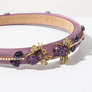 Detailed close-up of purple satin headband featuring jeweled bees and crystal chain trim