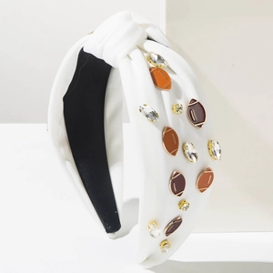 Detail eines weißen Knotenstirnbands mit Rugby-Anhängern und Kristallen auf Stativ