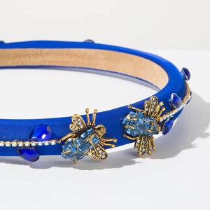 Close-up of blue fabric headband with crystal rhinestones and vintage gold bee details