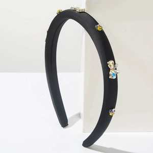 Détail d'un serre-tête noir rembourré avec papillon en strass colorés et fleurs