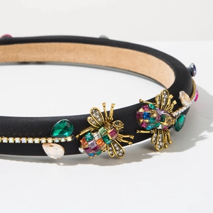 Detailed macro view of a vintage baroque headband with golden bees and colorful rhinestones