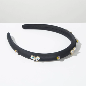 Détail d'un serre-tête en satin noir avec strass colorés et décoration nœud cristal