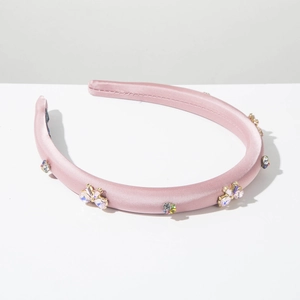 Détail d'un serre-tête en satin rose avec strass colorés et accents de papillon