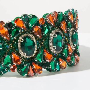Détail d'un serre-tête baroque vintage avec des pierres précieuses émeraude et ambre sur métal