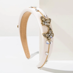 Macro shot of padded cream headband with gold butterfly ornaments and inlaid rhinestones