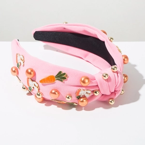 Détail d'un serre-tête rose noué avec de mignons breloques lapin, carotte et perles