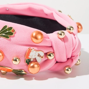 Détail du serre-tête rose noué avec breloque lapin, perles et texture tricotée