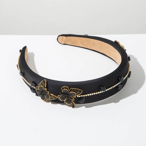 Detail of a thick padded velvet headband with black rhinestone gems and gold-edged bows