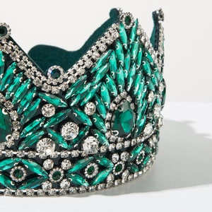 Macro view of luxurious green crystal crown featuring dense emerald rhinestones and white gems