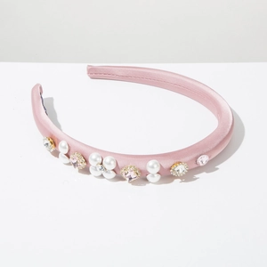 Detailed close-up of pink satin headband with white pearls and sparkling crystals