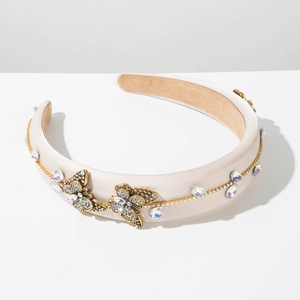 Detail of crystal butterfly headband with gold-tone rhinestones on beige satin fabric