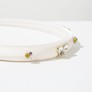 Détail d'un serre-tête en soie blanche orné de strass colorés et d'un nœud cristal