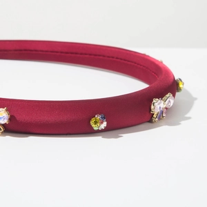 Gros plan détaillé du serre-tête en satin rouge foncé avec strass colorés et bijoux