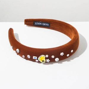 Détail du serre-tête en velours marron avec cristaux de cœur et étiquette Hand Made