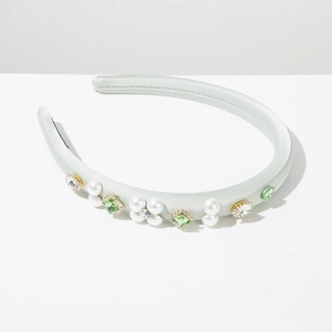Detailed view of mint green satin headband with handmade pearls and emerald rhinestones