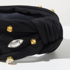 Detailaufnahme eines geknoteten schwarzen Haarreifs mit Strass und Football-Anhänger