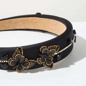 Detail of a padded black headband with gold crystal butterfly and large black gemstones