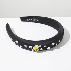 Détail d'un serre-tête noir rembourré avec des strass colorés et une étiquette