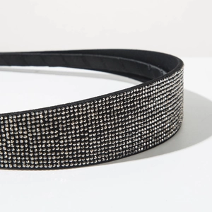 Detailed close-up of a slim black headband covered in multiple rows of sparkling rhinestones