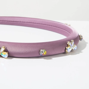 Gros plan d'un serre-tête en satin violet avec détails de papillons et cristaux brillants