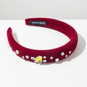 Détail d'un serre-tête en velours rouge fait main avec strass en forme de cœur et étoile