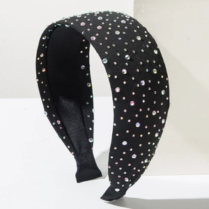Detail of a wide black headband with colorful rhinestones on a white geometric stand