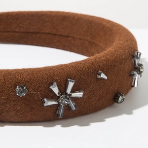 Close-up of brown wool headband featuring elegant grey crystal sunburst flower detail