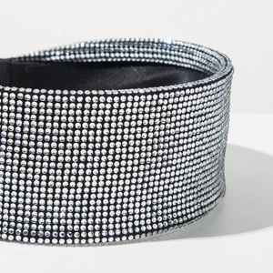 Close-up of sparkling white rhinestones on wide headband with black satin lining