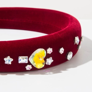 Gros plan d'un serre-tête en velours rouge avec strass colorés en forme de cœur