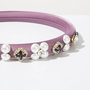 Detail of purple satin headband featuring faux pearls and square purple gemstones