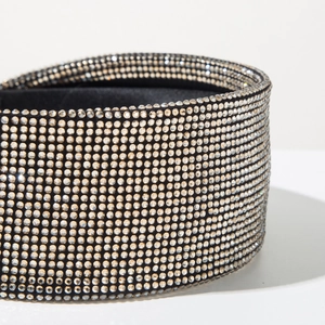 Macro detail of high-shine crystal rhinestones on wide velvet headband with luxury finish
